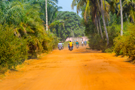 OUIDAH, BENIN - Jan 10, 2017: Unidentified Beninese people ride a motorbike on the street in rush hour from behind.  It's a popular way of transportationのeditorial素材