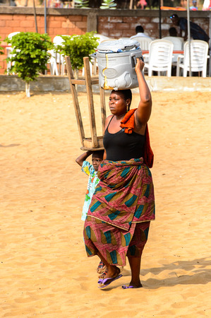 OUIDAH, BENIN - Jan 10, 2017: Unidentified Beninese woman carries a barrel on her head at the voodoo festival, which is anually celebrated on January, 10th.のeditorial素材