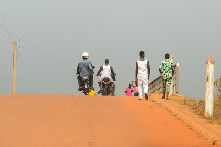 OUIDAH, BENIN - Jan 10, 2017: Unidentified Beninese people ride a motorbike on the street in rush hour from behind.  It's a popular way of transportationのeditorial素材