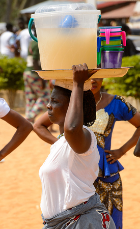 OUIDAH, BENIN - Jan 10, 2017: Unidentified Beninese  woman carries a bucket with liquid at the voodoo festival, which is anually celebrated on January, 10th.のeditorial素材