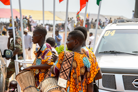 OUIDAH, BENIN - Jan 10, 2017: Unidentified Beninese men in colored suits carry drums at the voodoo festival, which is anually celebrated on January, 10th.のeditorial素材