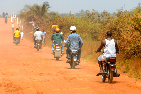 OUIDAH, BENIN - Jan 10, 2017: Unidentified Beninese people ride a motorbike on the road in rush hour from behind.  It's a popular way of transportationのeditorial素材