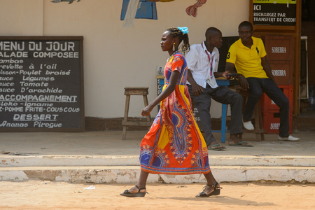OUIDAH, BENIN - Jan 10, 2017: Unidentified Beninese girl in colored dress walks on the street. Benin people suffer of poverty due to the bad economyのeditorial素材