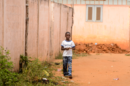 OUIDAH, BENIN - Jan 10, 2017: Unidentified Beninese young boy holds something in his hands. Benin children suffer of poverty due to the bad economyのeditorial素材