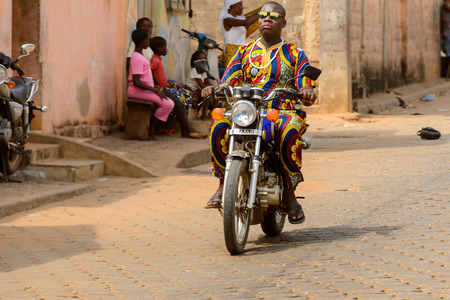 OUIDAH, BENIN - Jan 10, 2017: Unidentified Beninese man rides a motorbike on the street in rush hour. It's a popular way of transportationのeditorial素材