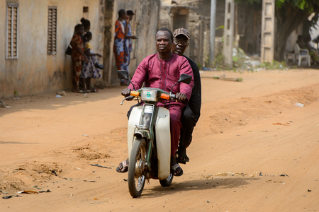 OUIDAH, BENIN - Jan 10, 2017: Unidentified Beninese people ride a motorbike on the street in rush hour. It's a popular way of transportationのeditorial素材