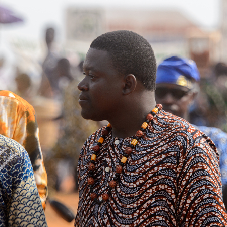 OUIDAH, BENIN - Jan 10, 2017: Unidentified Beninese man in colored clothes wears beads on his neck and looks away. Benin people suffer of poverty due to the bad economyのeditorial素材