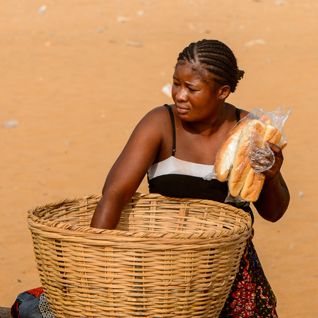 OUIDAH, BENIN - Jan 10, 2017: Unidentified Beninese woman picks up bread from basket at the voodoo festival, which is anually celebrated on January, 10th.のeditorial素材