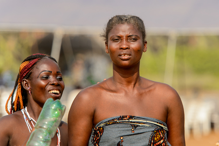 OUIDAH, BENIN - Jan 10, 2017: Unidentified Beninese woman smiles and holds a bottle at the voodoo festival, which is anually celebrated on January, 10th.のeditorial素材