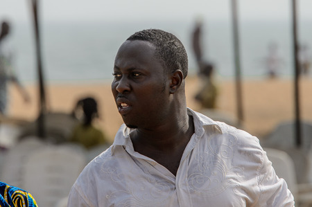 OUIDAH, BENIN - Jan 10, 2017: Unidentified Beninese man in white shirt looks away at the voodoo festival, which is anually celebrated on January, 10th.のeditorial素材