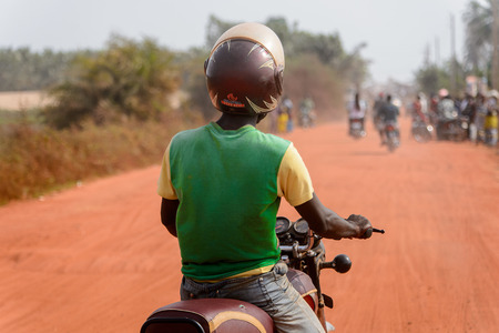 OUIDAH, BENIN - Jan 10, 2017: Unidentified Beninese man rides a motorbike on the street in rush hour. It's a popular way of transportationのeditorial素材