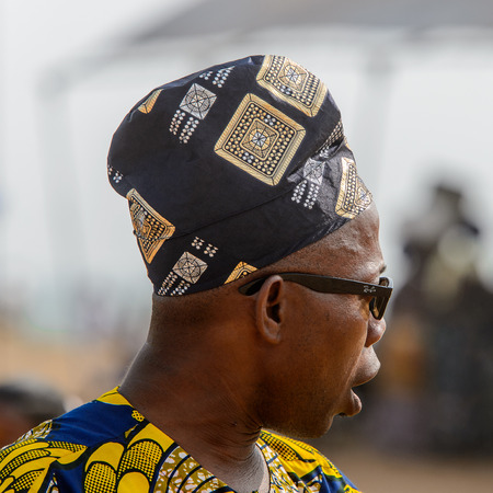OUIDAH, BENIN - Jan 10, 2017: Unidentified Beninese man in colored shirt with a hat and glasses at the voodoo festival, which is anually celebrated on January, 10th.のeditorial素材