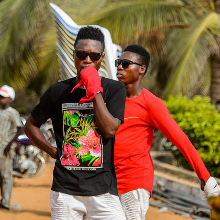 OUIDAH, BENIN - Jan 10, 2017: Unidentified Beninese men in colored clothes wear sunglasses. Benin people suffer of poverty due to the bad economyのeditorial素材