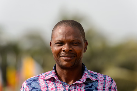 OUIDAH, BENIN - Jan 10, 2017: Unidentified Beninese man in colored shirt smiles at the voodoo festival, which is anually celebrated on January, 10th.のeditorial素材