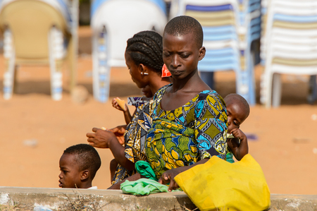 OUIDAH, BENIN - Jan 10, 2017: Unidentified Beninese woman in colored dress carries a baby at the voodoo festival, which is anually celebrated on January, 10th.のeditorial素材