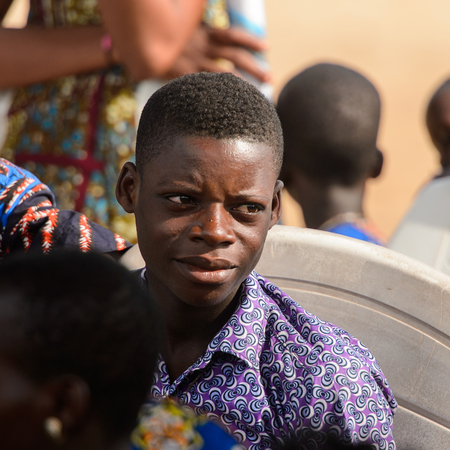 OUIDAH, BENIN - Jan 10, 2017: Unidentified Beninese young boy in colored shirt looks away at the voodoo festival, which is anually celebrated on January, 10th.のeditorial素材
