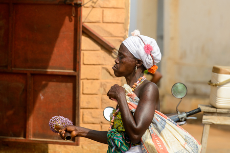 OUIDAH, BENIN - Jan 10, 2017: Unidentified Beninese woman in white headscarf and colored clothes on the street. Benin people suffer of poverty due to the bad economyのeditorial素材
