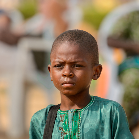 OUIDAH, BENIN - Jan 10, 2017: Unidentified Beninese  little boy in green shirt frowns at the voodoo festival, which is anually celebrated on January, 10th.のeditorial素材