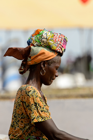 OUIDAH, BENIN - Jan 10, 2017: Unidentified Beninese woman in colored clothes and headscarf walks on the street. Benin people suffer of poverty due to the bad economyのeditorial素材