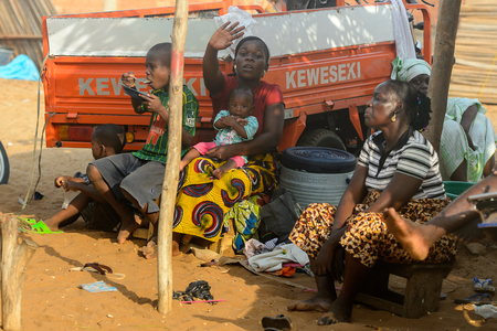 OUIDAH, BENIN - Jan 10, 2017: Unidentified Beninese women with children rest at the local market. Benin people suffer of poverty due to the bad economyのeditorial素材