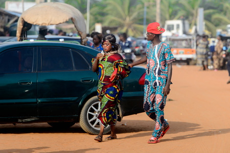 OUIDAH, BENIN - Jan 10, 2017: Unidentified Beninese couple in colored clothes walk at the local market. Benin people suffer of poverty due to the bad economyのeditorial素材