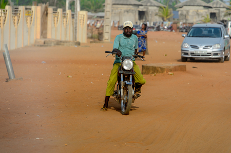 OUIDAH, BENIN - Jan 10, 2017: Unidentified Beninese man rides a motorcycle at the local market....