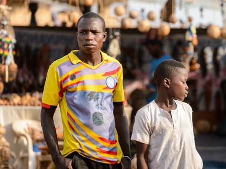 OUIDAH, BENIN - Jan 10, 2017: Unidentified Beninese man in colored shirt looks around at the local market. Benin people suffer of poverty due to the bad economyのeditorial素材
