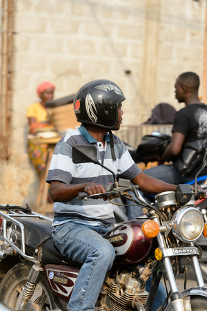 OUIDAH, BENIN - Jan 10, 2017: Unidentified Beninese man rides a motorcycle. Benin people suffer of poverty due to the bad economyのeditorial素材
