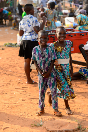 OUIDAH, BENIN - Jan 10, 2017: Unidentified Beninese little girl and boy in colored suits smile at the local market. Benin children suffer of poverty due to the bad economyのeditorial素材
