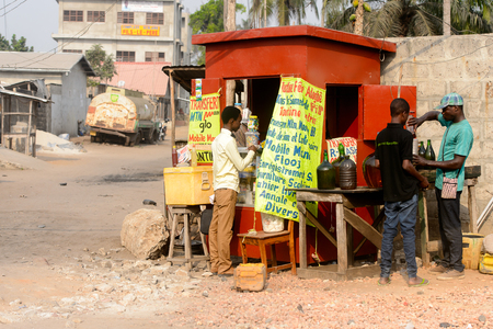 OUIDAH, BENIN - Jan 10, 2017: Unidentified Beninese man pours some liquid on the street. Benin people suffer of poverty due to the bad economy.のeditorial素材