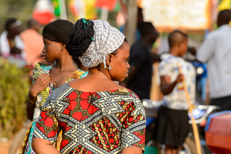 OUIDAH, BENIN - Jan 10, 2017: Unidentified Beninese woman with braids in colored clothes at the local market. Benin people suffer of poverty due to the bad economyのeditorial素材