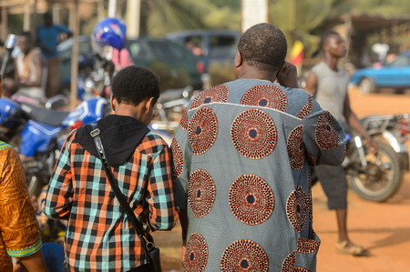 OUIDAH, BENIN - Jan 10, 2017: Unidentified Beninese group of people in colored clothes from behind at the local market. Benin people suffer of poverty due to the bad economyのeditorial素材