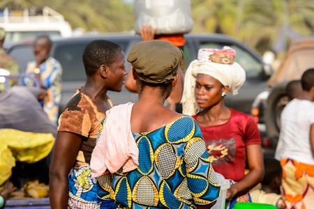 OUIDAH, BENIN - Jan 10, 2017: Unidentified Beninese woman in colored dress from behind at the local market. Benin people suffer of poverty due to the bad economyのeditorial素材