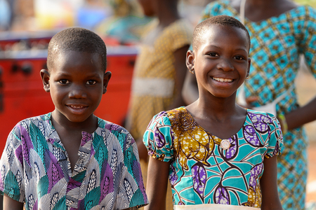 OUIDAH, BENIN - Jan 10, 2017: Unidentified Beninese little girl and boy in colored suits smile at the local market. Benin children suffer of poverty due to the bad economyのeditorial素材
