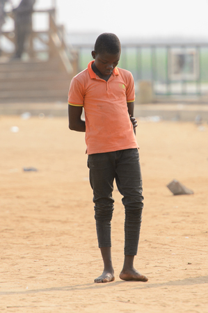 OUIDAH, BENIN - Jan 10, 2017: Unidentified Beninese boy looks down on the street. Benin people suffer of poverty due to the bad economyのeditorial素材
