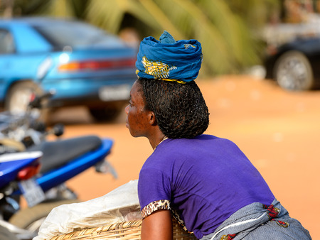 OUIDAH, BENIN - Jan 10, 2017: Unidentified Beninese woman in colored clothes from behind at the local market. Benin people suffer of poverty due to the bad economyのeditorial素材