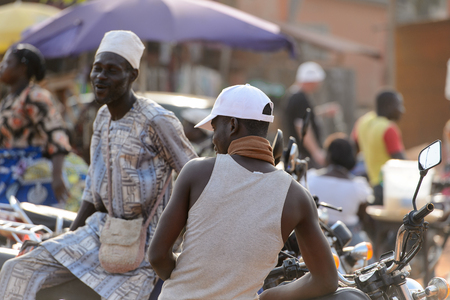 OUIDAH, BENIN - Jan 10, 2017: Unidentified Beninese man in white hat smiles at the local market. Benin people suffer of poverty due to the bad economyのeditorial素材