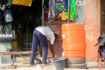 OUIDAH, BENIN - Jan 10, 2017: Unidentified Beninese man bends down on the street. Benin people suffer of poverty due to the bad economyのeditorial素材