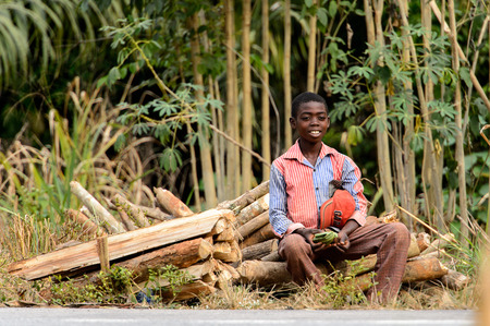 KUMASI, GHANA - Jan 16, 2017: Unidentified Ghanaian boy sits near the tree branches. Children of Ghana suffer of poverty due to the bad economyのeditorial素材