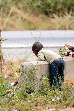 KUMASI, GHANA - Jan 16, 2017: Unidentified Ghanaian little boy bends down over the fence. Children of Ghana suffer of poverty due to the bad economyのeditorial素材