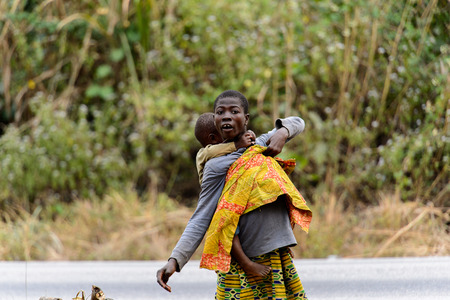 KUMASI, GHANA - Jan 16, 2017: Unidentified Ghanaian woman carries her little boy on her back. People of Ghana suffer of poverty due to the bad economyのeditorial素材