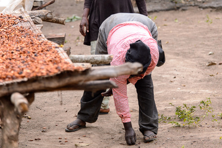 KUMASI, GHANA - Jan 16, 2017: Unidentified Ghanaian woman in pink shirt and black headscarf bends down. People of Ghana suffer of poverty due to the bad economyのeditorial素材