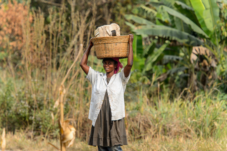 KUMASI, GHANA - Jan 16, 2017: Unidentified Ghanaian woman carries a basket on her head along the road . People of Ghana suffer of poverty due to the bad economyのeditorial素材