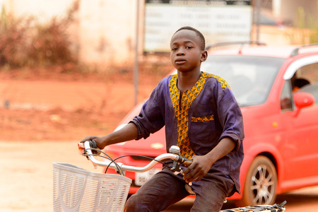 KUMASI, GHANA - Jan 16, 2017: Unidentified Ghanaian liitle boy rides a bicycle on the street. Children of Ghana suffer of poverty due to the bad economyのeditorial素材