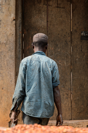 KUMASI, GHANA - Jan 16, 2017: Unidentified Ghanaian man walks on the street from behind. People of Ghana suffer of poverty due to the bad economyのeditorial素材