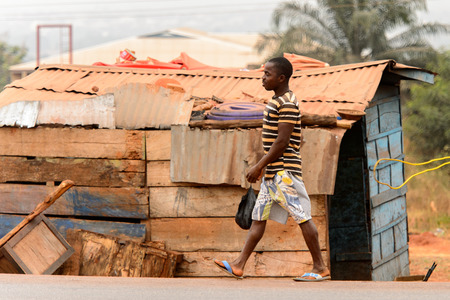 KUMASI, GHANA - Jan 16, 2017: Unidentified Ghanaian man walks by the shack along the road . People of Ghana suffer of poverty due to the bad economyのeditorial素材