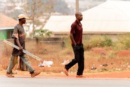 KUMASI, GHANA - Jan 16, 2017: Unidentified Ghanaian men walk along the road. People of Ghana suffer of poverty due to the bad economyのeditorial素材