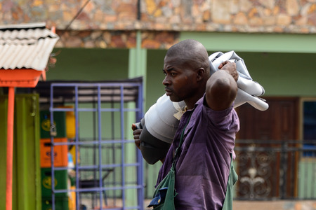 KUMASI, GHANA - Jan 16, 2017: Unidentified  Ghanaian man in purple shirt with mustache carries some clothes. People of Ghana suffer of poverty due to the bad economyのeditorial素材