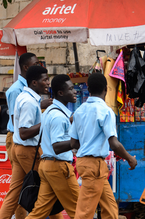KUMASI, GHANA - Jan 16, 2017: Unidentified Ghanaian students in blue shirts and mustard pants walk on the street. People of Ghana suffer of poverty due to the bad economyのeditorial素材