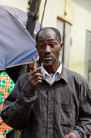 KUMASI, GHANA - Jan 16, 2017: Unidentified Ghanaian man in dark shirt walks along the street. People of Ghana suffer of poverty due to the bad economyのeditorial素材